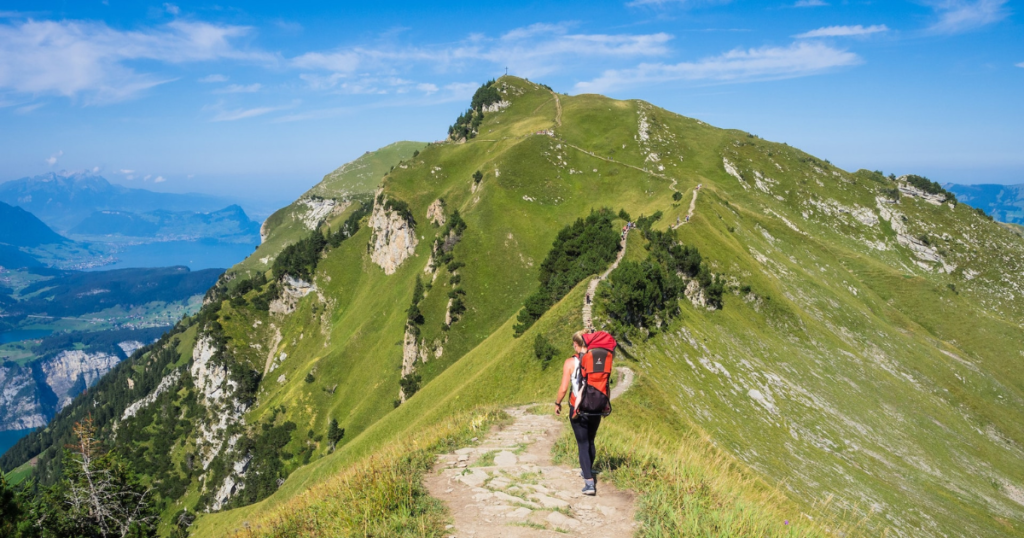 backpacker girl with backpack walks a path on top of mountain chain