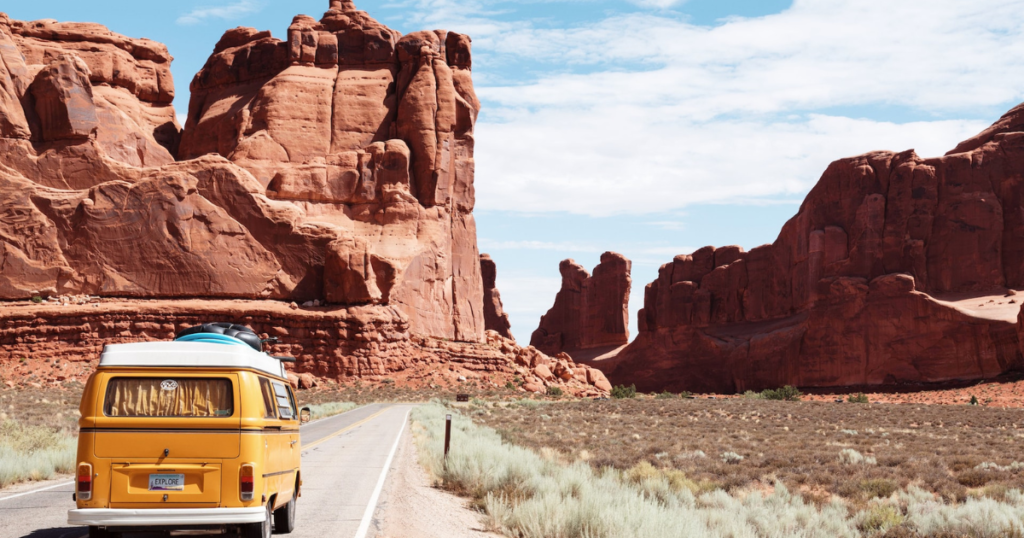 yellow camper driving in national park in usa between big rocks