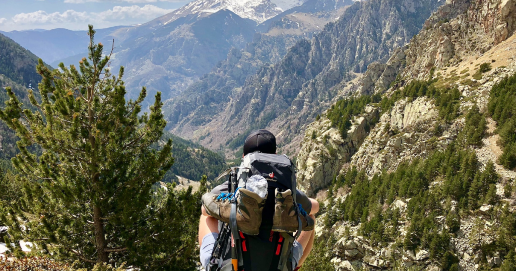 Backpacker with backpack in mountains after a hike, enjoying the nice view and the landscape while doing a world trip