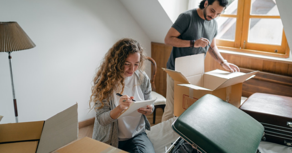 man and woman packing stuff in boxes and luggage. moving out of the flat and leaving for a world trip