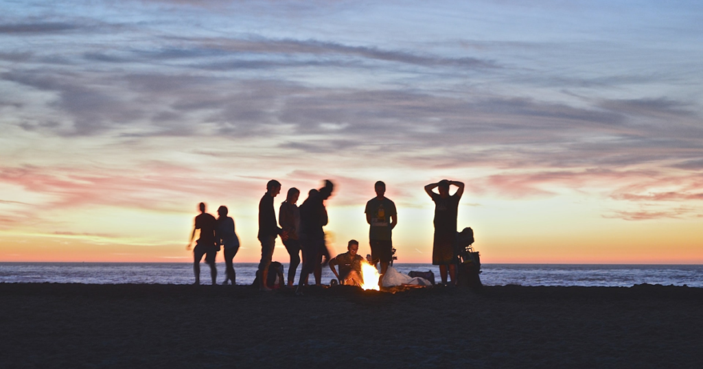 beach landscape during night, people in the picture sitting together around a campfire