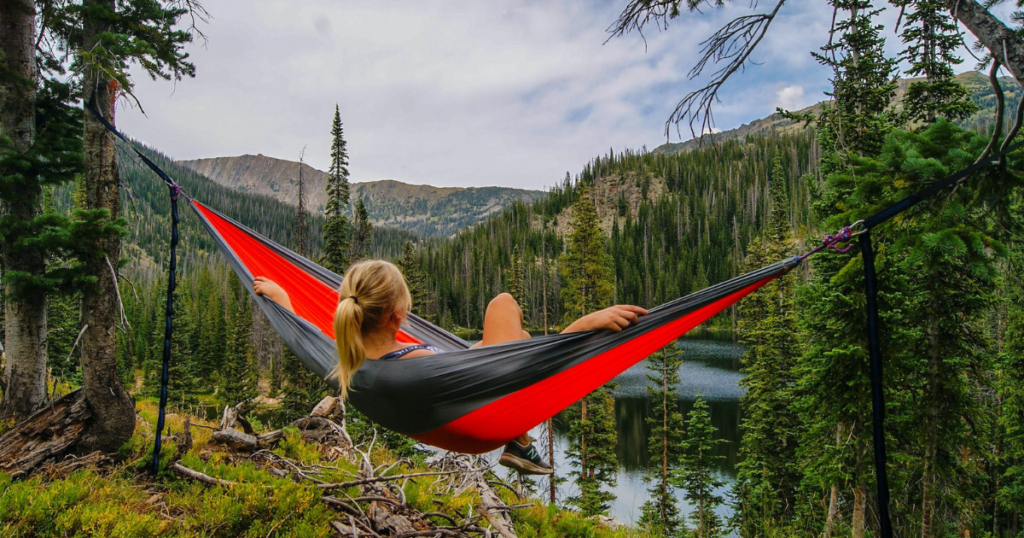 blonde woman in a hammock in the mountains with view over a lake