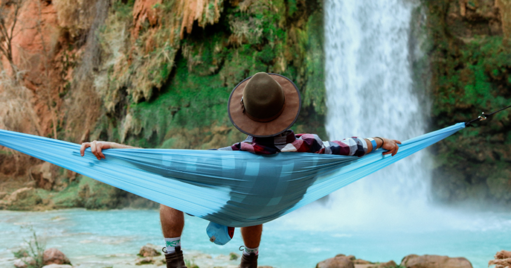 man is chilling in a hammock with view on a waterfall. the hammock can be a christmas present for a traveler