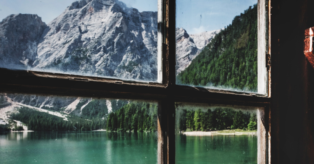 picture shows the view out of a window over a lake to the mountains. picture serves to decorate the article about the best travel hacks