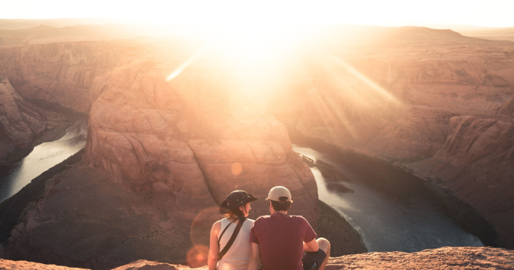 picture of a couple sitting in arizona in horseshoe bend and enyoing beautiful view. 