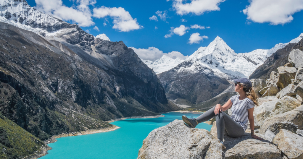 woman is sitting on top of a rock in the mountains with beautiful view. This picture decorates the article about the best travel hacks