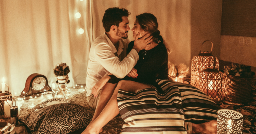 couple is sitting on a carpet and looking in each others eyes. romantic date at home for valentinesday