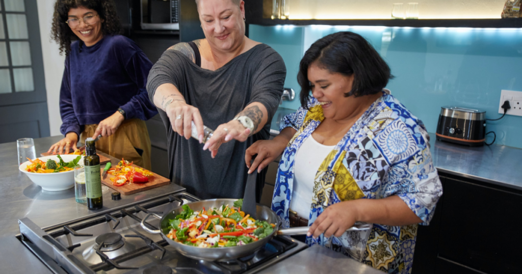 Persons in a kitchen cooking something at the heat. It is green, healty, vegan foog. This is a trick for vegan travel 