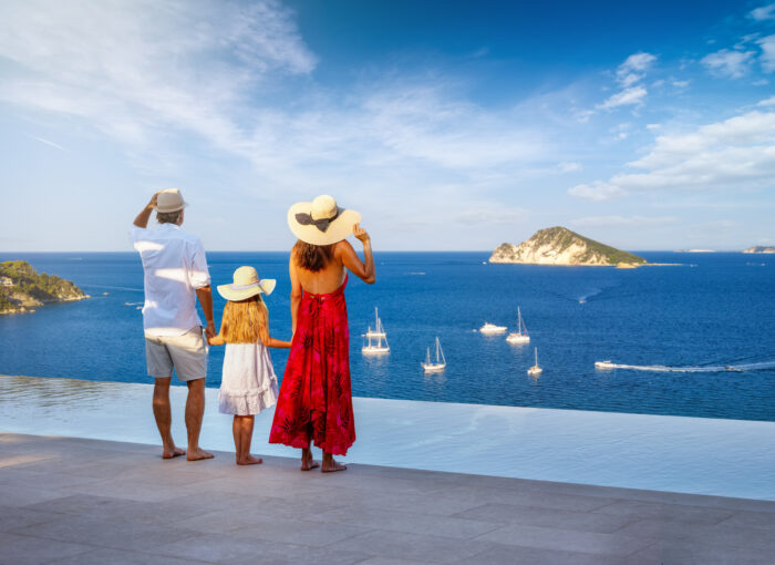 A family on summer holidays enjoys the sunset view over the ionian sea from their swimming pool, best personalized travel companies for custom itineraries