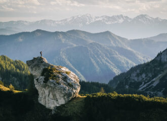 Hiker on the top of the rock in the mountains, at sunrise