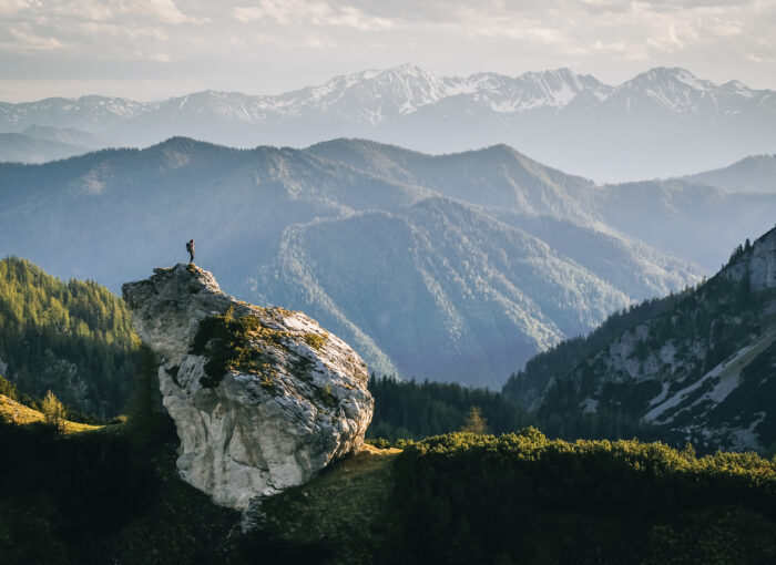 Hiker on the top of the rock in the mountains, at sunrise