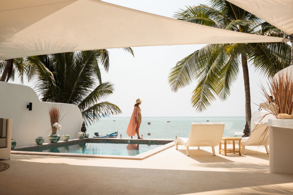 Woman enjoy a leisurely moment by the swimming pool at a luxurious villa on the beach, best personalized travel company for custom itineraries
