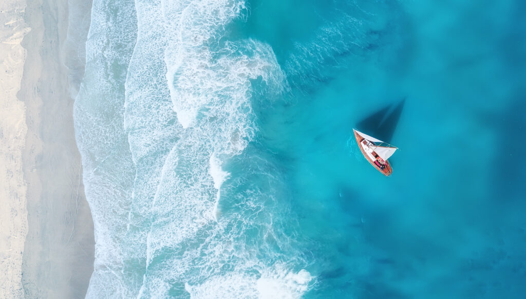 Yacht on the water surface from top view. Turquoise water background from top view, best personalized travel companies for custom itineraries